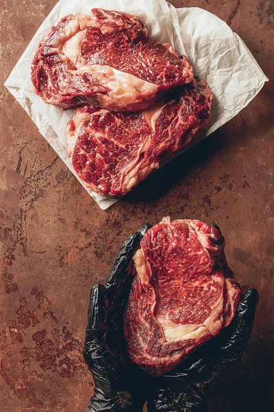 Imagem cortada de açougueiro segurando carne crua para bife nas mãos — Fotografia de Stock