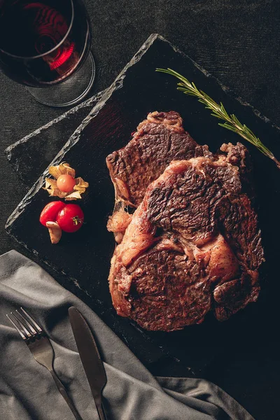 Vista superior de bifes cozidos em tábuas de corte, copo de vinho tinto em mesa na cozinha — Fotografia de Stock