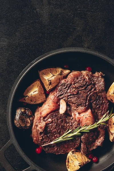 Top view of roasted steak with lemons and berries on frying pan in kitchen — Stock Photo