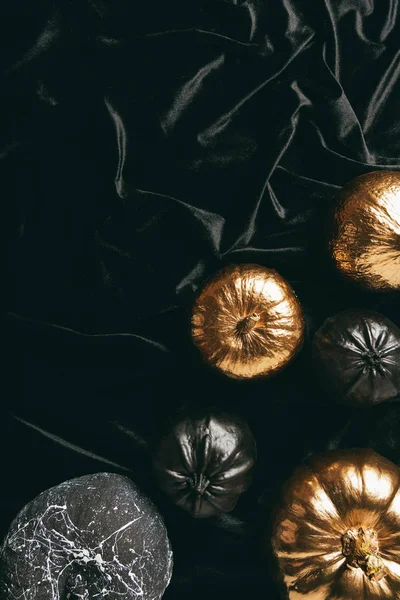 Vista superior de calabazas doradas y negras tradicionales en tela negra, diseño de halloween - foto de stock