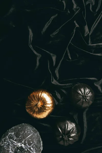 Vista superior de abóboras pintadas de preto e dourado decorativas em pano preto para festa de Halloween tradicional — Fotografia de Stock