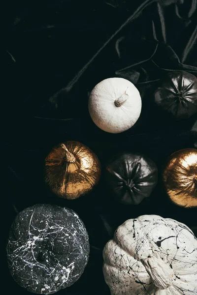 Top view of festive decorative golden, black and white painted pumpkins on black cloth for halloween party — Stock Photo