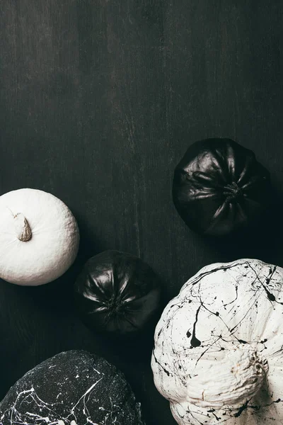 Top view of black and white pumpkins with paint splatters on dark background with copy space — Stock Photo
