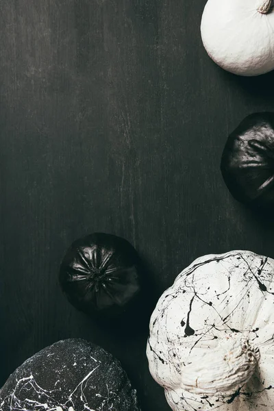 Top view of black and white pumpkins with paint splatters on dark background with copy space — Stock Photo