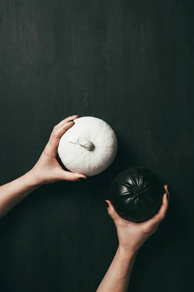 Vista cortada de mulher segurando halloween abóboras preto e branco em mãos — Fotografia de Stock