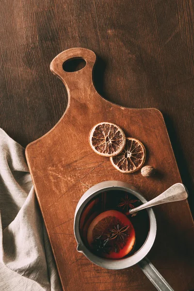 Vista superior del tradicional vino caliente caliente casero con especias en la tabla de cortar en la mesa de madera - foto de stock