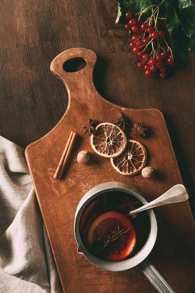 Вид горячего глинтвейна со специями и ягодами вибурнума на деревянном фоне — стоковое фото