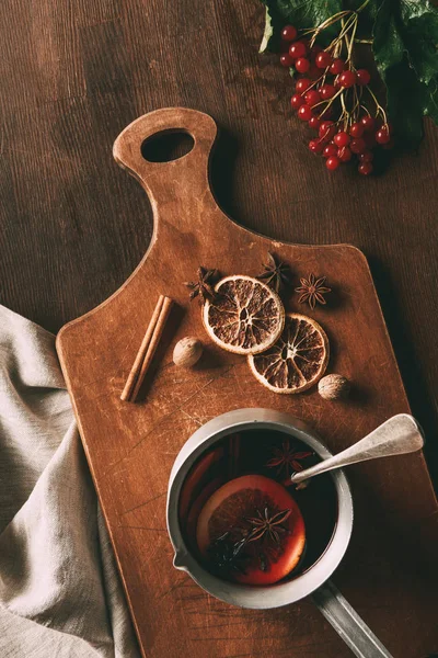 Top view of hot mulled wine with spices and viburnum berries on wooden background — Stock Photo