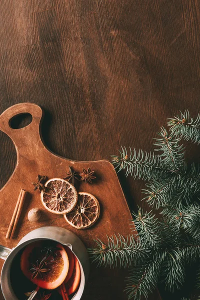 Top view of homemade mulled wine with spices on cutting board on wooden background with pine branch — Stock Photo