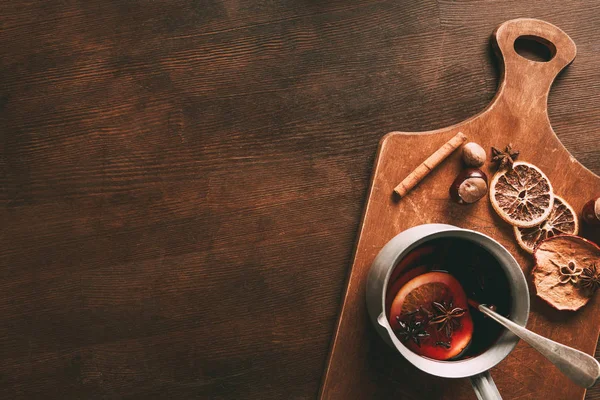 Top view of homemade hot mulled wine with spices on cutting board on wooden background — Stock Photo