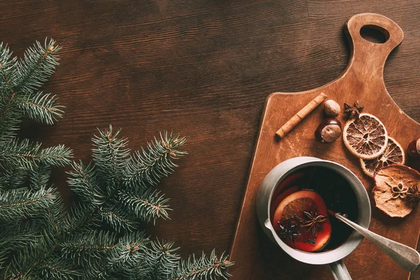 Vue du dessus du vin chaud fait maison avec des épices sur fond en bois avec branche de pin — Photo de stock