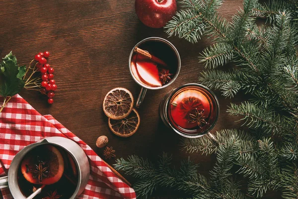 Top view of glass cups with homemade hot spiced wine on wooden background with viburnum berries and fir branches — Stock Photo