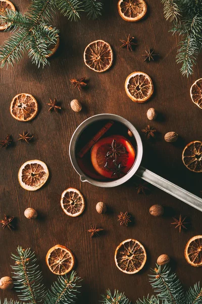 Top view of mulled wine with dried orange slices and spices on wooden background with fir branches — Stock Photo