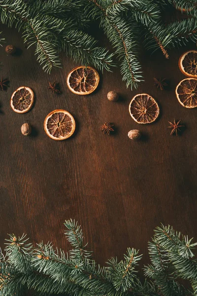 Top view of christmas spices on wooden background with fir branches and copy space — Stock Photo