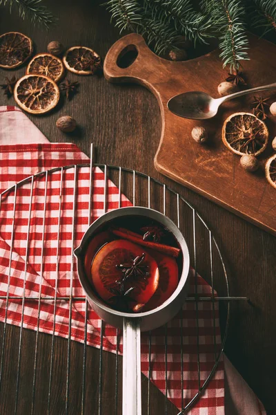Домашнє гаряче глінтвейнне вино в каструлі зі спеціями на дерев'яному фоні — стокове фото