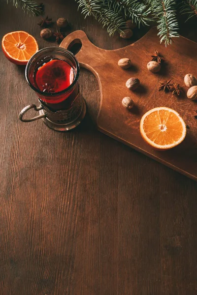 Chaud vin chaud chaud avec des épices et orange dans une tasse en verre sur planche à découper en bois — Photo de stock