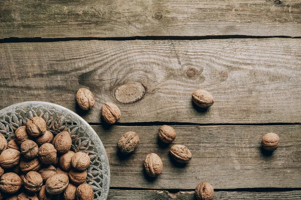 Top view of ripe organic walnuts and plate on wooden table — Stock Photo