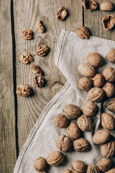 Vue de dessus de délicieuses noix biologiques et tissu sur table en bois — Photo de stock