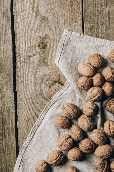 Top view of whole tasty healthy walnuts on cloth on wooden table — Stock Photo