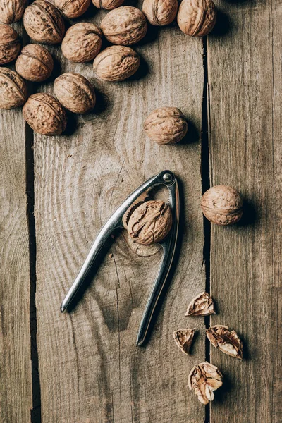 Top view of tasty healthy walnuts and nutcracker on wooden table — Stock Photo