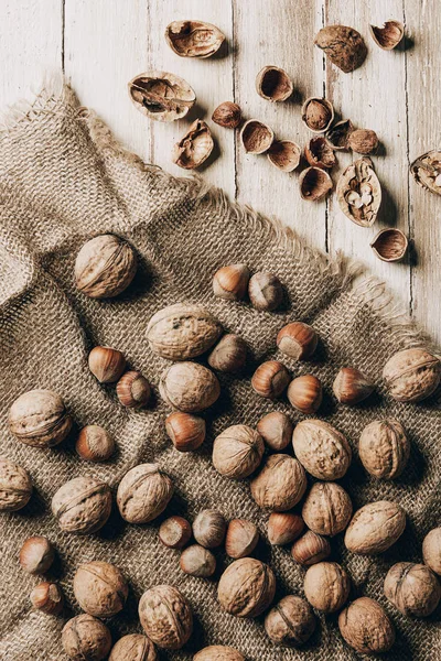 Vue de dessus des noisettes et des noix sur le sac sur la table en bois — Photo de stock