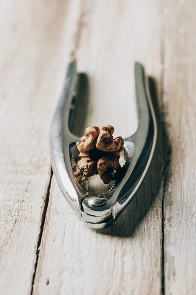 Close-up view of nutcracker with healthy tasty walnut on wooden table — Stock Photo