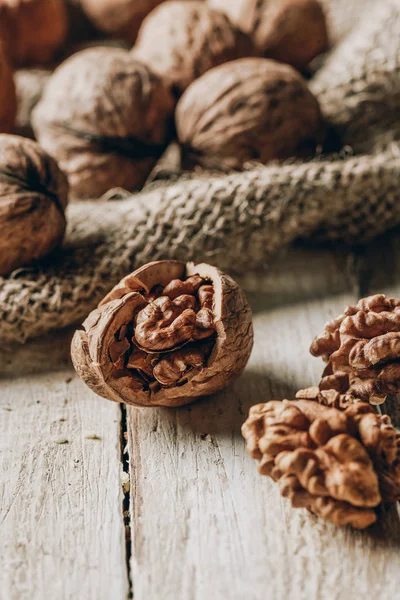 Vue rapprochée des noix entières et fissurées et du sac sur une table en bois — Photo de stock