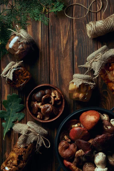 Vista superior de deliciosos champiñones enlatados y frescos sobre mesa de madera - foto de stock