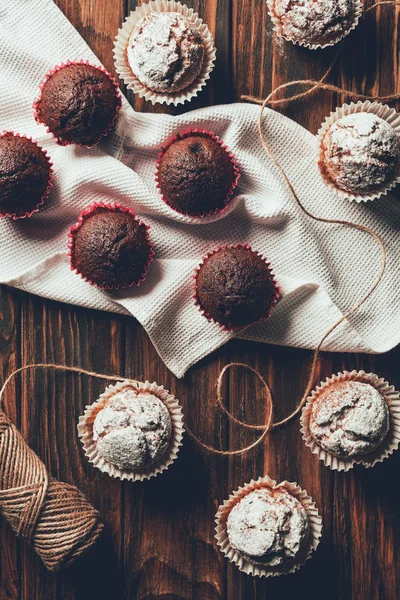 Draufsicht auf leckere gebackene Muffins und Garnspule auf Holztisch in Bäckerei — Stockfoto