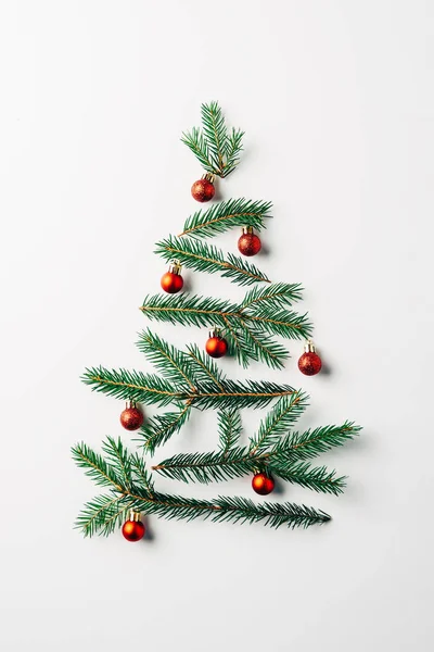 Top view of pine branches arranged in christmas tree with toys on white background — Stock Photo