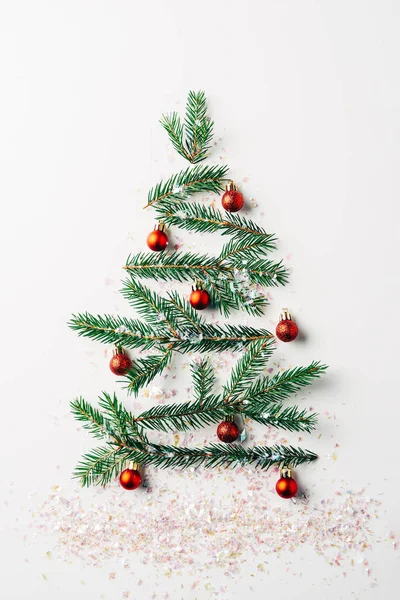 Top view of green pine branch decorated as festive christmas tree with glitters on white background — Stock Photo