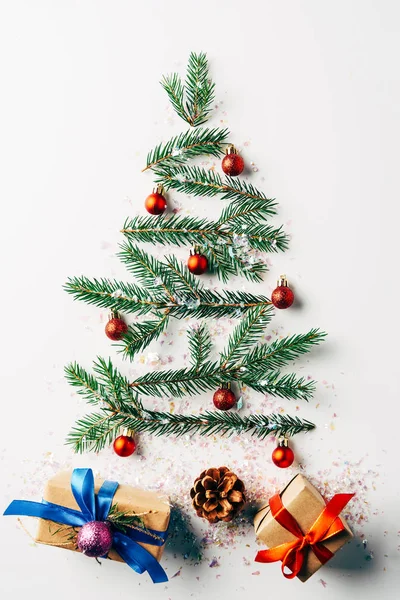 Vue de dessus de la branche de pin vert décoré comme arbre de Noël festif avec des cadeaux et des paillettes sur fond blanc — Photo de stock