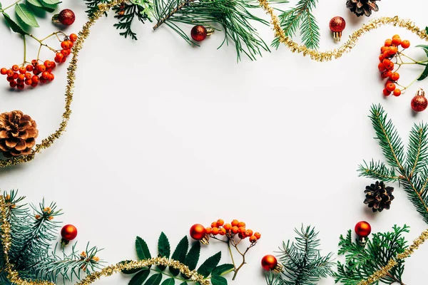 Tendido plano con arreglo festivo de ramas de pino, espino cerval de mar común y decoraciones de navidad sobre mesa blanca - foto de stock