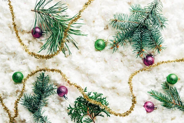 Tendido plano con ramas de pino, juguetes de Navidad y guirnalda festiva sobre fondo de lana de algodón blanco - foto de stock