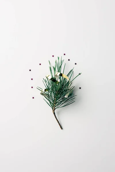 Vue de dessus de la petite branche de pin avec ruban et paillettes sur la surface blanche — Photo de stock