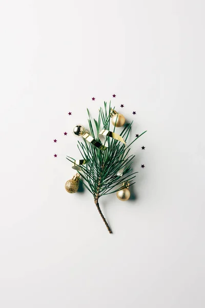 Vue de dessus de la petite branche de pin avec ruban et jouets de Noël sur surface blanche — Photo de stock