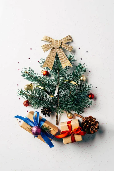 Vue de dessus de la branche de pin vert décoré comme arbre de Noël festif avec des cadeaux et arc sur fond blanc — Photo de stock