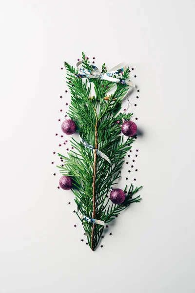 Top view of green pine branch decorated with christmas toys and ribbon as christmas tree on white backdrop — Stock Photo