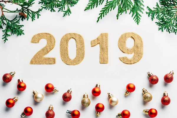 Top view of 2019 year sign, pine tree branches and christmas balls on white background — Stock Photo