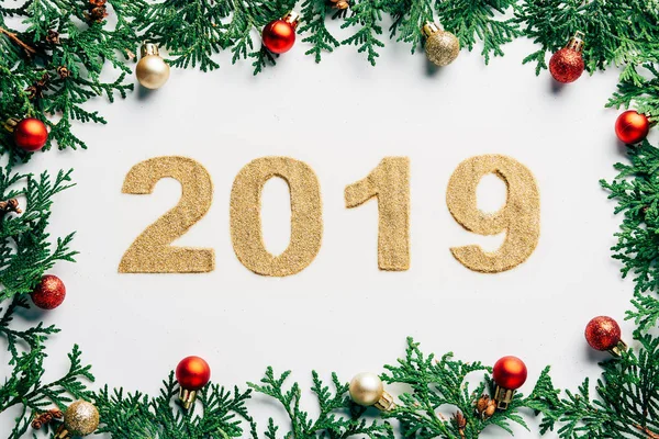 Top view of 2019 year sign, pine tree branches and christmas balls on white background — Stock Photo