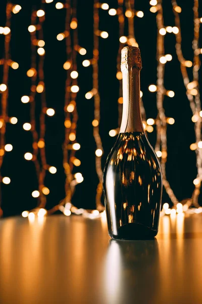 Bouteille de champagne sur fond de guirlande, concept de Noël — Photo de stock