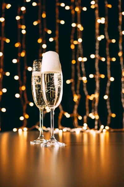 Copos de champanhe na grinalda luz de fundo, conceito de natal — Fotografia de Stock