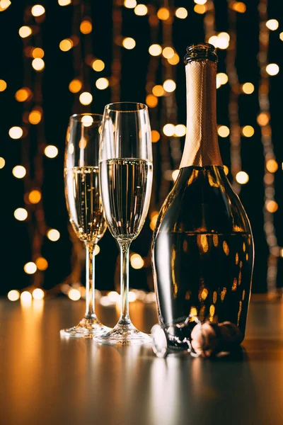 Selective focus of champagne bottle and glasses on garland light background, christmas concept — Stock Photo