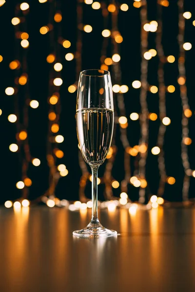 Una copa de champán sobre fondo claro guirnalda, concepto de Navidad - foto de stock