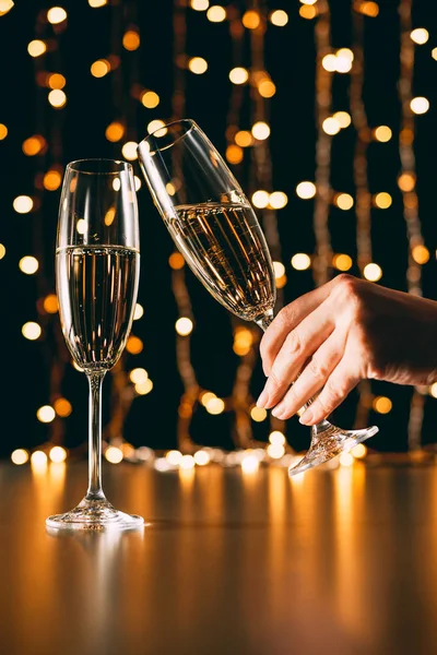 Imagem cortada de mulher clinking com copo de champanhe no fundo de luz guirlanda, conceito de natal — Fotografia de Stock