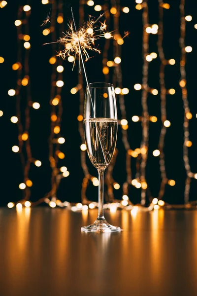 Champagne with christmas sparkle on garland light background — Stock Photo