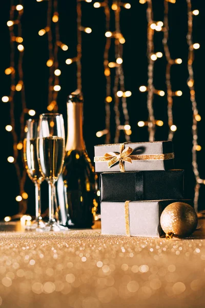 Nivel de superficie de champán y regalos sobre fondo claro guirnalda, concepto de Navidad - foto de stock