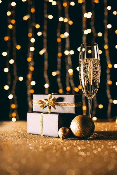 Nivel de superficie de champán en vidrio y cajas de regalo sobre fondo claro guirnalda, concepto de Navidad - foto de stock
