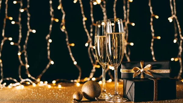 Copas de champán, adornos y regalos sobre fondo claro guirnalda, concepto de Navidad - foto de stock