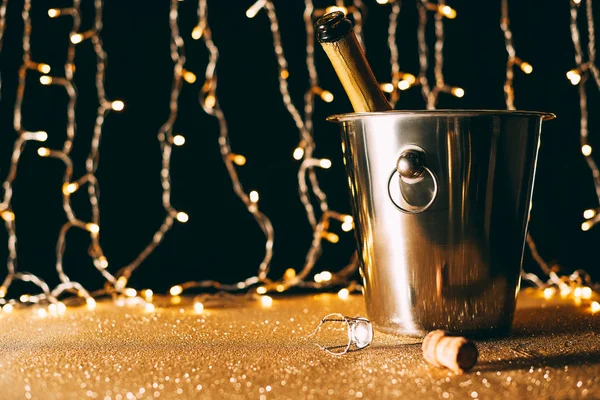 Champagnerflasche im Eimer auf Lichtergirlanden Hintergrund, Weihnachtskonzept — Stockfoto